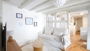A modern living room with a sofa, a round wooden coffee table, and a television on a wooden stand. - To complete (Strasbourg)