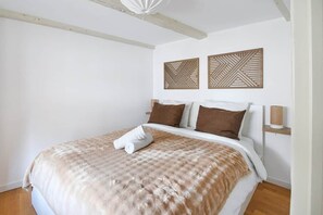 A bedroom with a large bed, two wall-mounted light fixtures, and decorative wall panels. - To complete (Strasbourg)