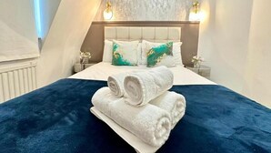 A bedroom with a bed, pillows, and rolled towels. - Apartment at Albert House, Kennington (London)