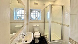 A bathroom with a glass-enclosed shower, a sink, a toilet, and a window. - Apartment at Albert House, Kennington (London)
