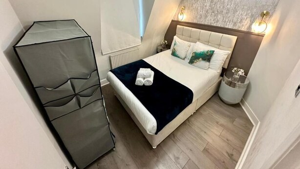 A bedroom with a bed, bedside lamps, a window, and a wall-mounted light fixture. - Apartment at Albert House, Kennington (London)