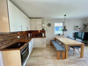 Eine moderne Küche mit weißen Schränken, einer Holz Arbeitsplatte und einem eingebauten Backofen.