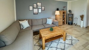 Una sala de estar con sofá, mesa de centro, decoración en la pared, lámpara, estantería y chimenea.
