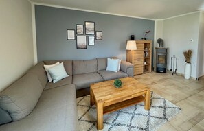 Ein Wohnzimmer mit Sofa, Couchtisch, Wandbildern, einer Lampe, einem Bücherregal und einem Kamin.