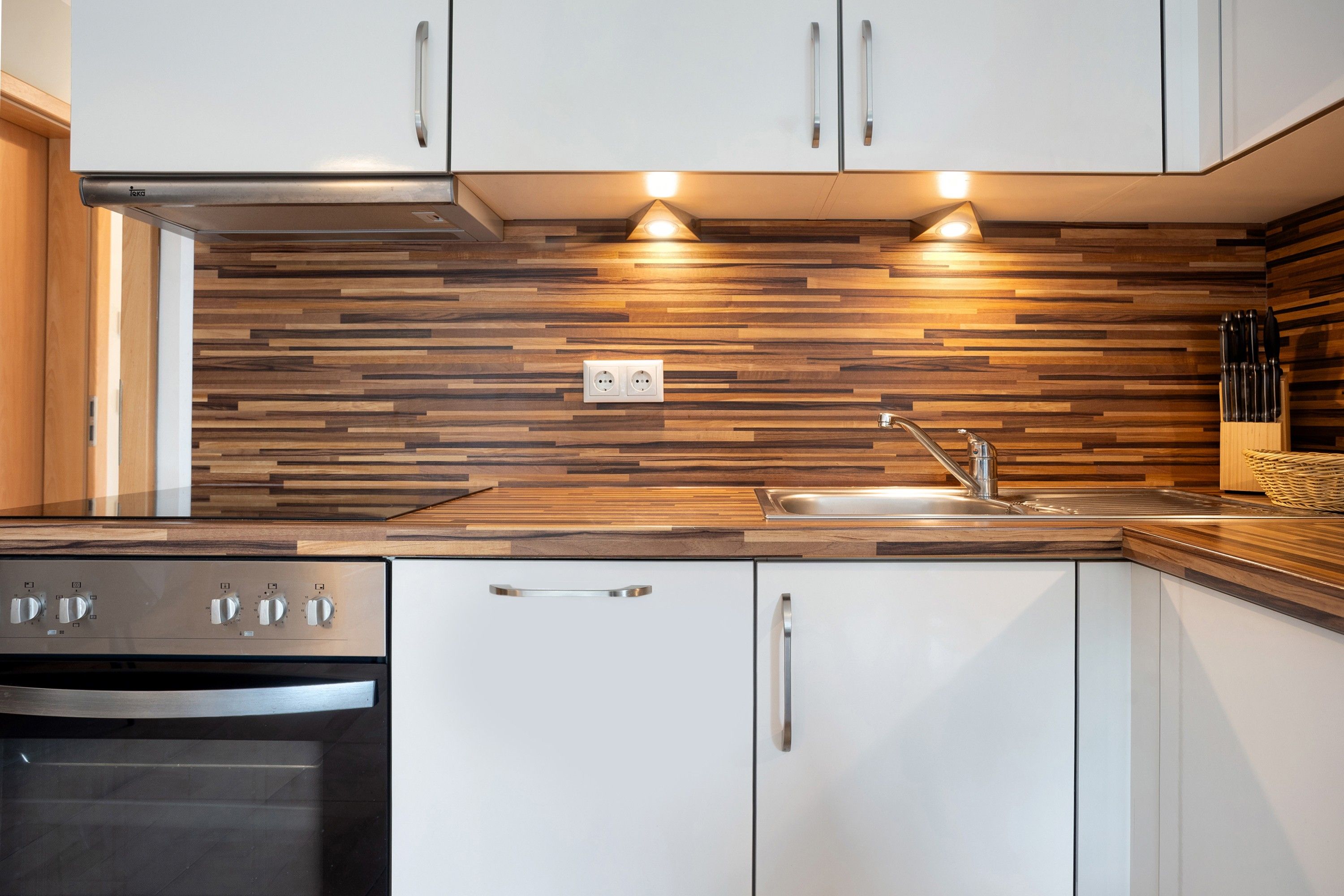 A modern kitchen with a wood-patterned backsplash, stainless steel appliances, and a built-in sink.