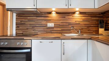 Eine moderne Küche mit einer holzstruktur versehenen Spritzschutzwand, Edelstahlgeräten und einer integrierten Spüle.
