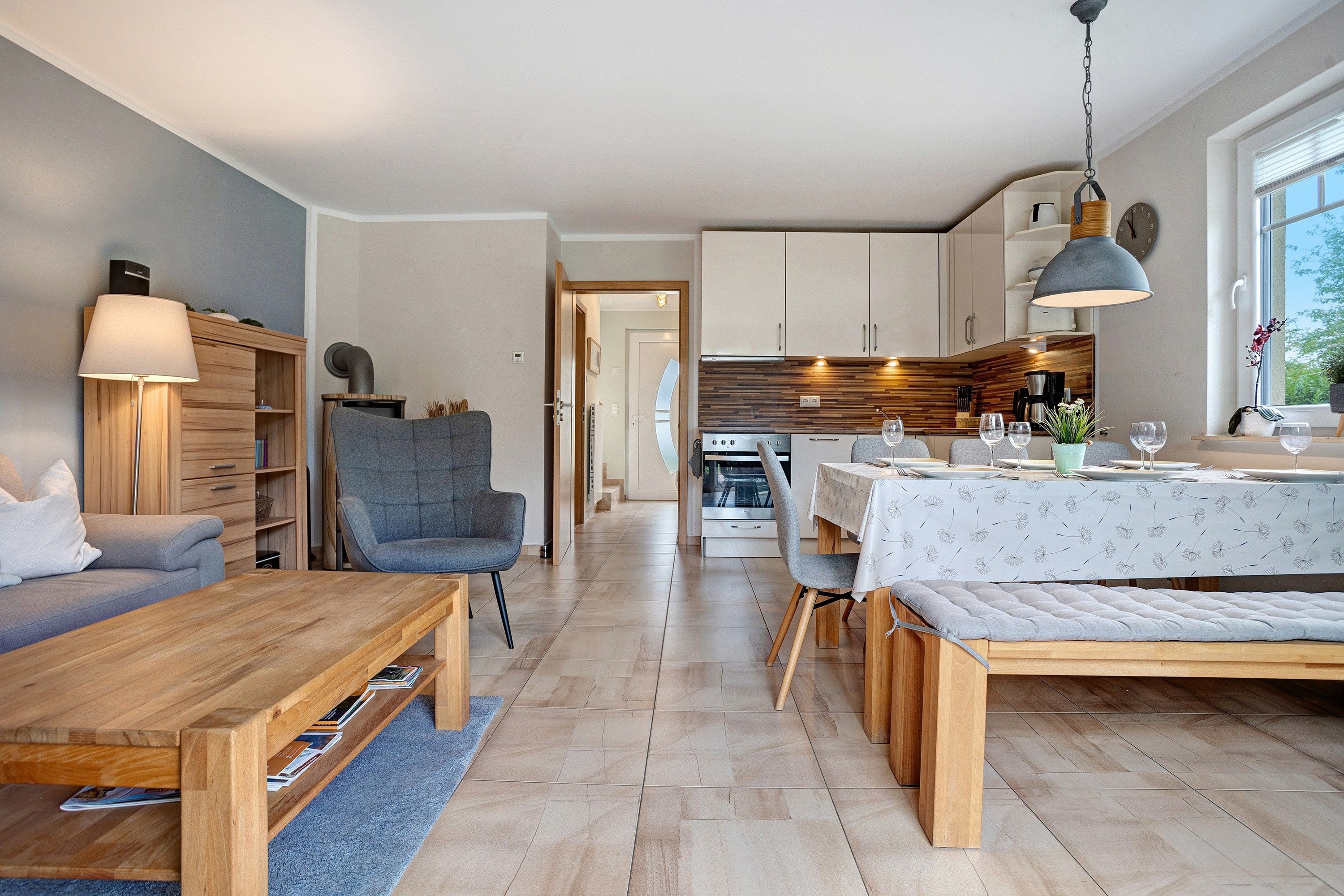 A modern living room with a sofa, a wooden coffee table, and a reading area with a bookshelf.