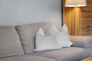 Un sofá gris con un cojín blanco y una lámpara de pie con pantalla blanca.