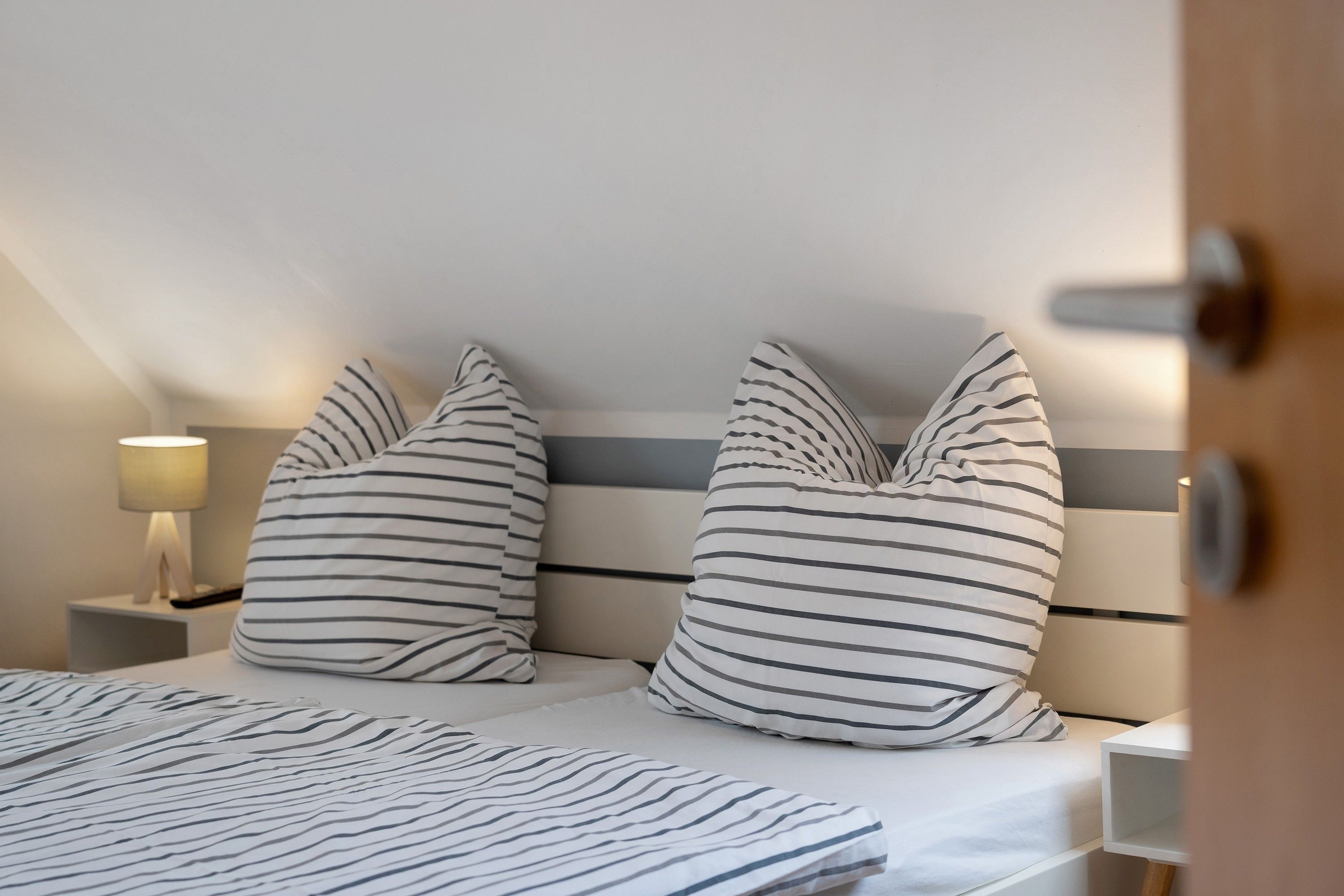 Ein Schlafzimmer mit einem Bett, zwei Kissen, einem Nachttisch und einer Lampe.