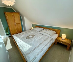 Ein Schlafzimmer mit einem Bett, einem Holzschrank, Nachttischen und einer Topfpflanze.