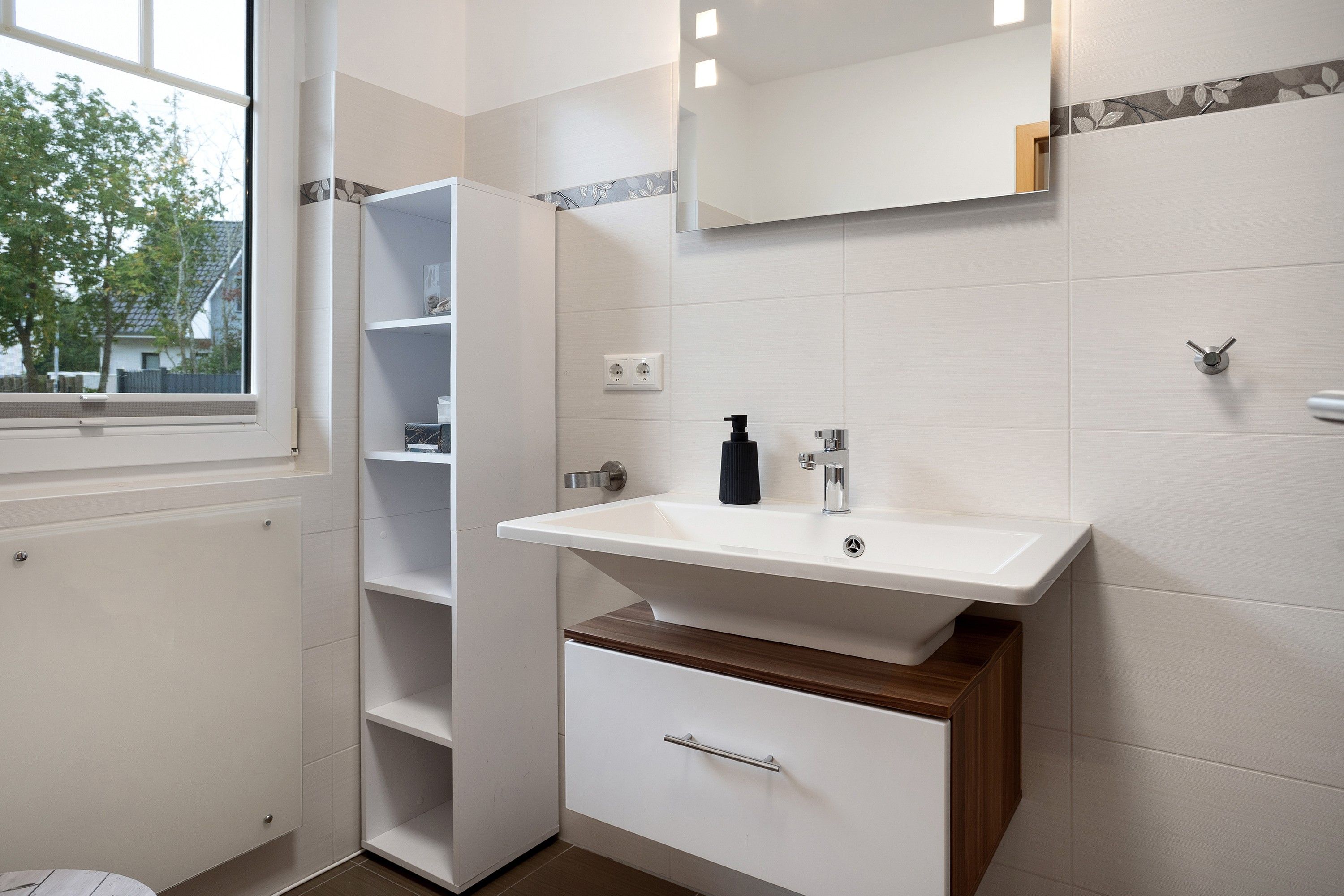 Une salle de bain avec un lavabo blanc, un miroir et un meuble en bois en dessous.