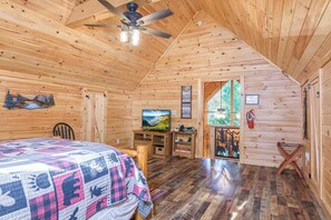 L’intérieur d’une cabane comprend un lit, un téléviseur et une fenêtre donnant sur la forêt.