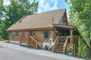 Eine Blockhütte mit Veranda, Treppe und einem kleinen Garten.