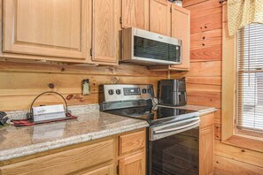 A kitchen with wooden cabinets, a microwave, a stove, and an oven. - Smoky Mtn Lake Escape | Hot Tub | Sleeps 7 (Sevierville)