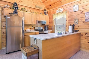 Eine Holzhütte mit einer Küche, inklusive Kühlschrank, Mikrowelle, Herd und Holzschränken.