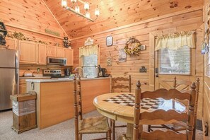 A wooden cabin interior with a kitchen, dining area, and a checkered table. - Smoky Mtn Lake Escape | Hot Tub | Sleeps 7 (Sevierville)