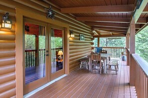 Eine Holzhütte mit Veranda, einem Tisch und Stühlen sowie einem Schild, das auf eine Unterkunft hinweist.