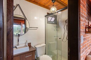 Ein modernes Badezimmer mit einer Glasdusche, einem weißen Waschbecken und einer Holzwaschtischunterschrank.