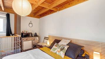 Une chambre à coucher avec un lit, des lampes de chevet, une petite table avec un micro-ondes et une fenêtre avec des rideaux.
