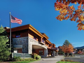 Ein Gebäude des Grand Residence Club mit einer Steinfassade, hölzernen Balkonen und einer amerikanischen Flagge.
