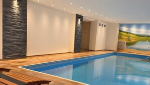 A swimming pool with wooden deck seating and a mural of a landscape.