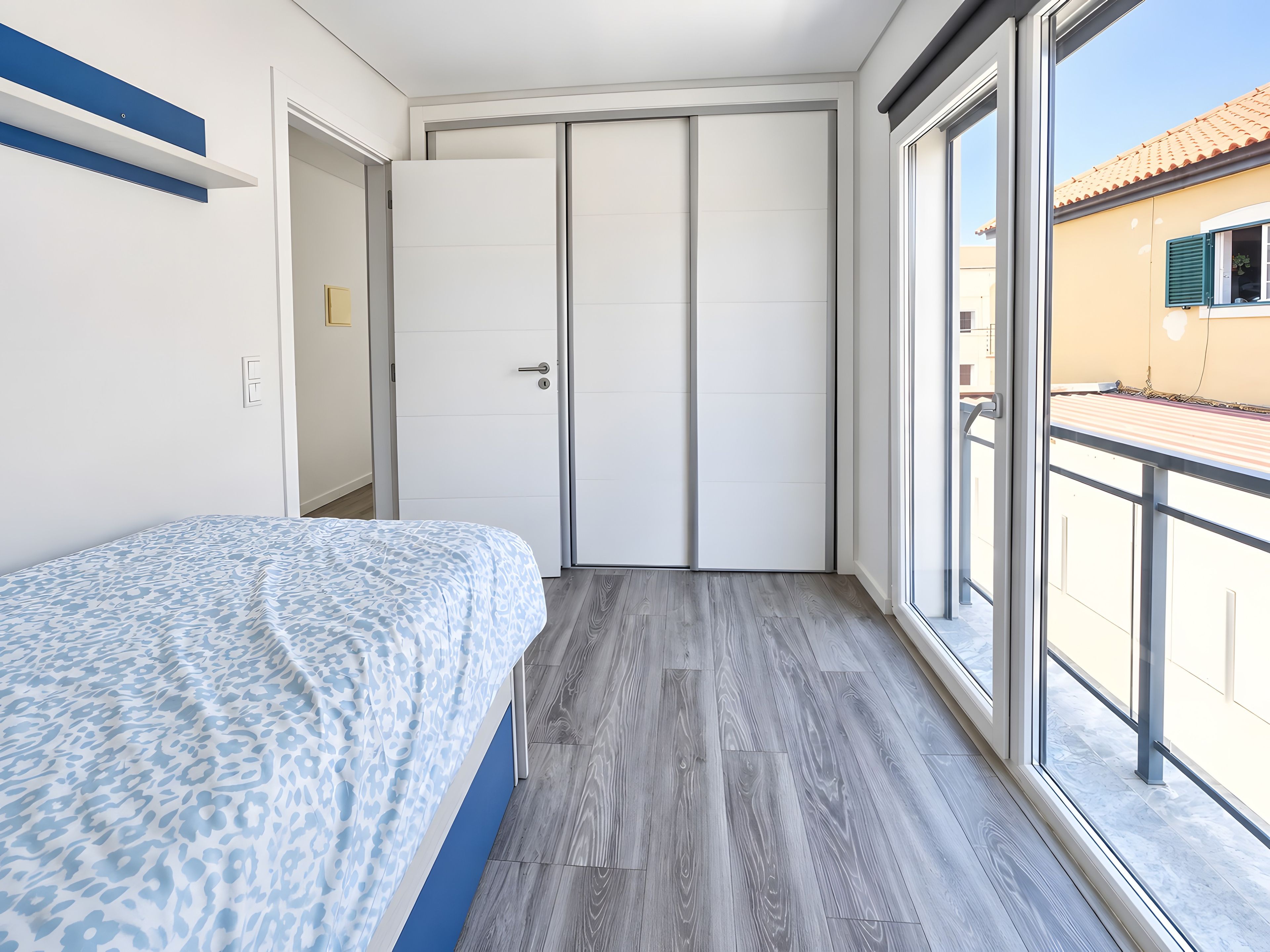 Quarto com cama, guarda-roupa e varanda.