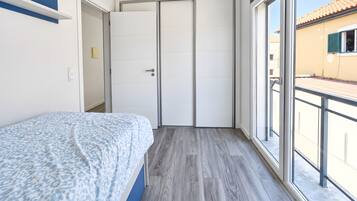Quarto com cama, guarda-roupa e varanda.