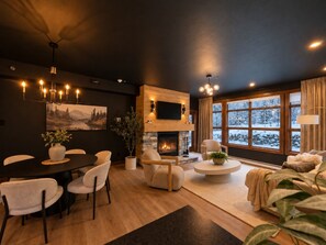 A modern living room with a fireplace, a dining area, and a large window with a view of a snowy landscape.