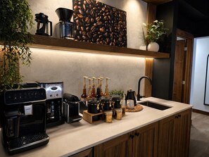A kitchen with a coffee machine, a coffee grinder, and various coffee containers. - Tremblant Prestige - Les Eaux 217-5A (Mont-Tremblant)