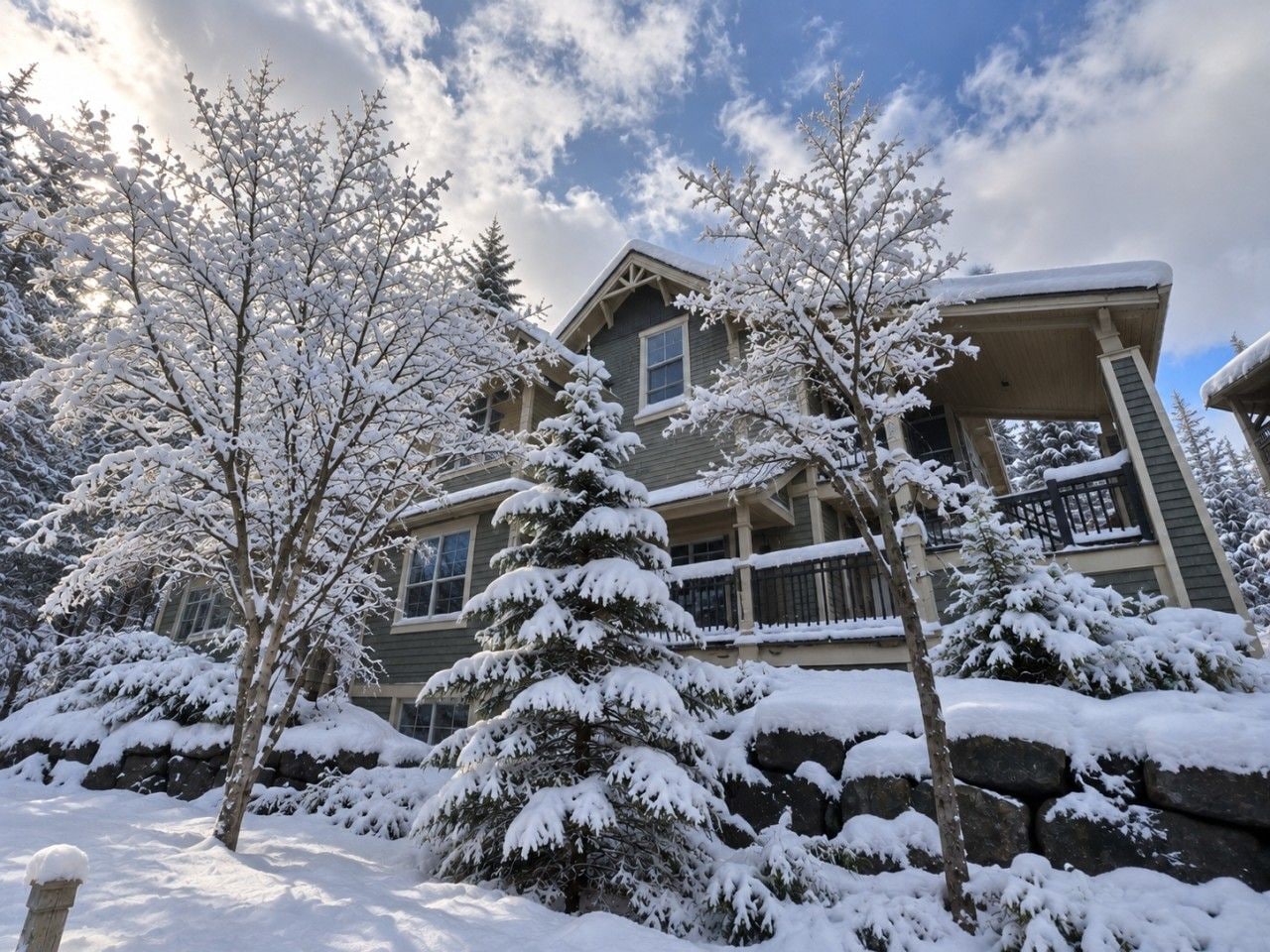 A two-story house with a porch and snow-covered trees.