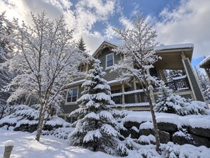 A two-story house with a porch and snow-covered trees. - Tremblant Prestige - Les Eaux 217-5A (Mont-Tremblant)