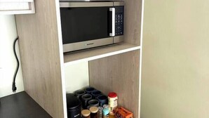 A kitchen with a microwave on the upper shelf and various kitchen items on the lower shelf. - Prime Curaçao Getaway - 9 min/Beach & Downtown (Willemstad)