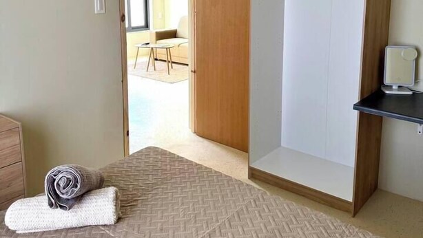 A bedroom with a bed, a wardrobe, a hanging light fixture, and a view into another room. - Prime Curaçao Getaway - 9 min/Beach & Downtown (Willemstad)