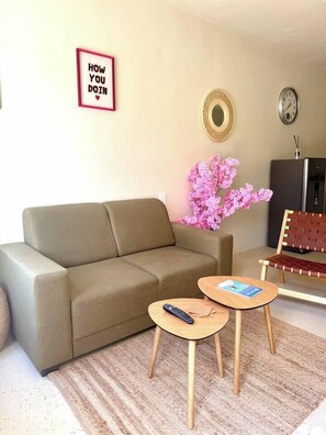 A living room with a sofa, two small tables, a chair, a clock, a decorative mirror, and a framed sign. - Prime Curaçao Getaway - 9 min/Beach & Downtown (Willemstad)