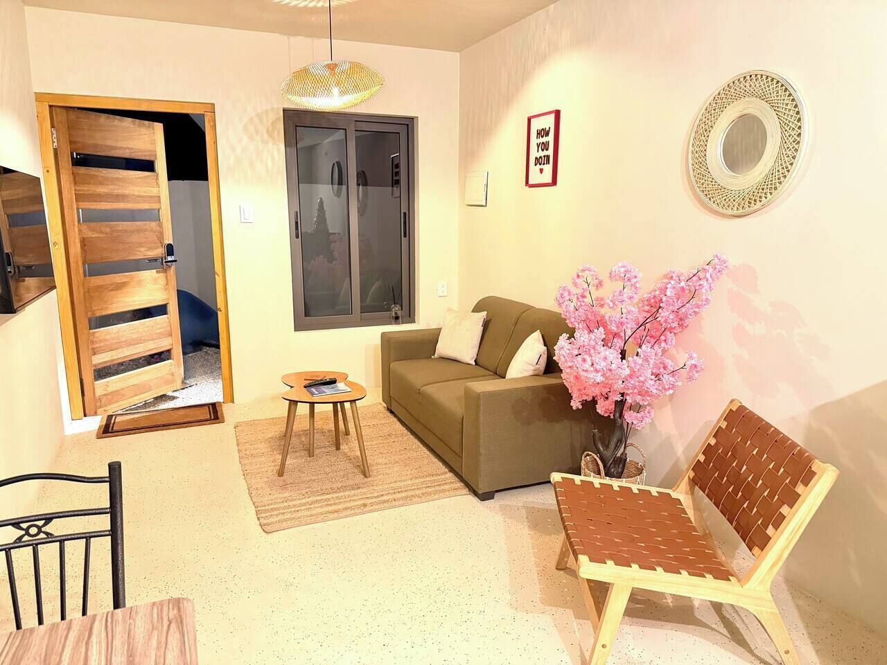 Uma sala de estar com sofá, uma mesinha, uma cadeira, uma porta e um espelho fixado na parede.