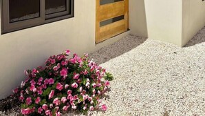 A modern building with a large window, a wooden door, and a gravel driveway. - Prime Curaçao Getaway - 9 min/Beach & Downtown (Willemstad)