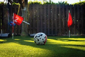 A soccer ball on a grassy lawn with two red flags and a wooden fence in the background. - Eden Luxury - 3 bedroom house in lovely Richardson, DFW Area (Richardson)