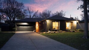 Ein Wohnhaus mit Garage, einer gut beleuchteten Haustür und einem angelegten Garten.