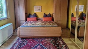 A bedroom with a bed, a large mirror, and a window.