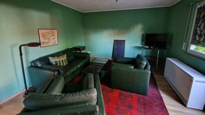Una sala de estar con sofá, mesa de centro, televisor y radiador.