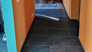 Un pasillo con paredes anaranjadas, piso de baldosas y un cuadro enmarcado en la pared.
