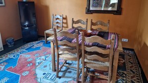 Un comedor con una mesa, sillas, un refrigerador y un tapete estampado.