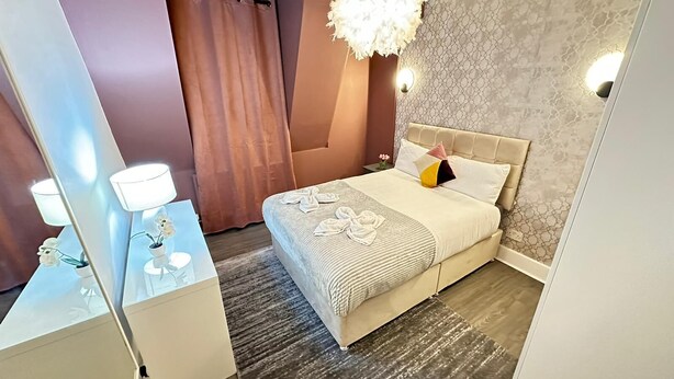 Une chambre  à coucher avec un lit, une table de chevet, un miroir, un lustre et un rideau.