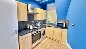 Une cuisine compacte équipée d’un lave-linge, d’un four à micro-ondes et d’une cuisinière.