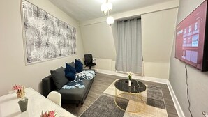 Un salon moderne avec un canapé, une table basse, un téléviseur et un tableau accroché au mur.