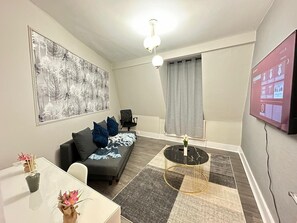 Ein modernes Wohnzimmer mit einer Couch, einem Couchtisch, einem Fernseher und einem Bild an der Wand.