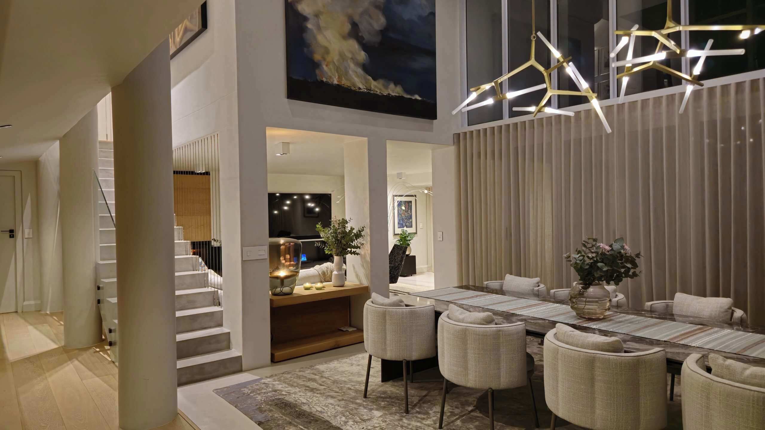 Un intérieur moderne comprenant un coin repas, un escalier et des œuvres d’art.