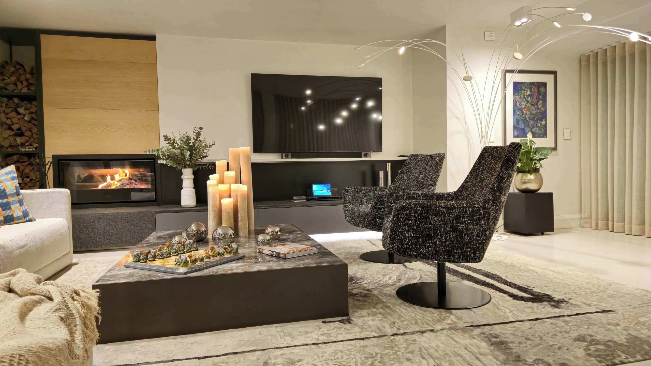 Un salon moderne doté d’une cheminée, d’un téléviseur à écran plat, d’une table basse agrémentée d’objets décoratifs et de meubles contemporains.