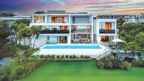 Ein modernes, mehrgeschossiges Haus mit Schwimmbad, umgeben von viel Grün.