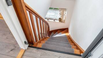 Eine Holztreppe mit Handlauf und Teppichstufen, die zu einer Zwischenebene führt.